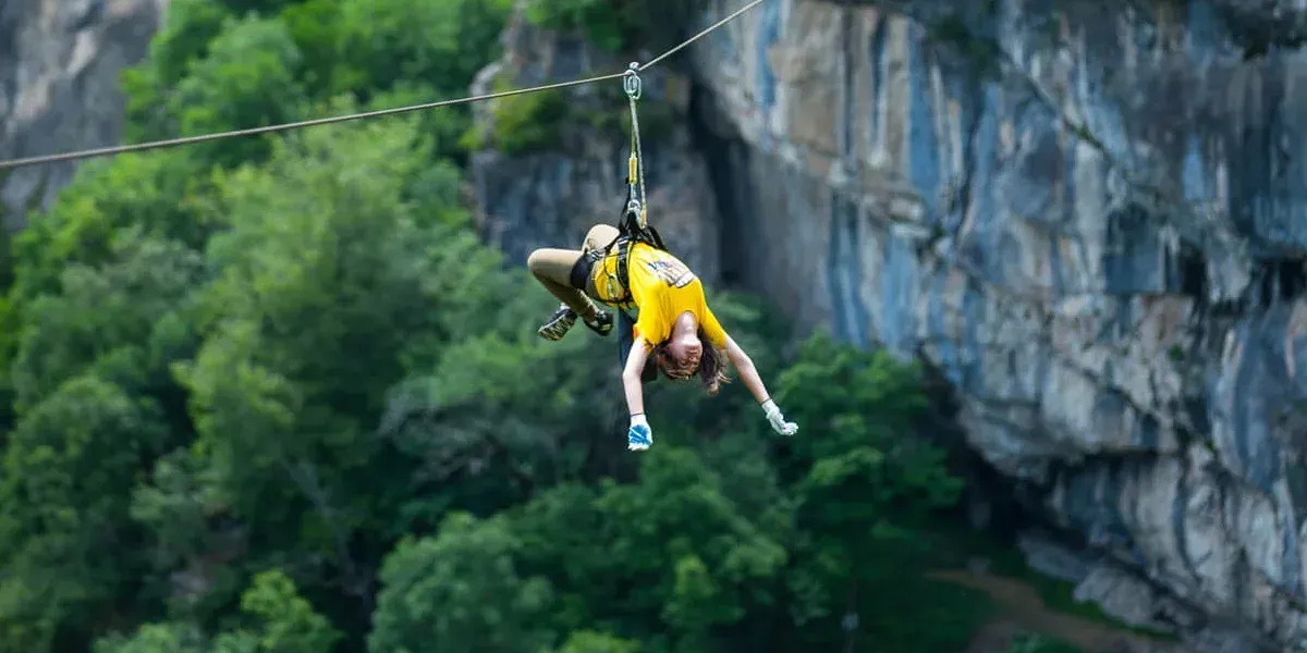 Zipline rider flying above the forested gorge at Yell Extreme Park